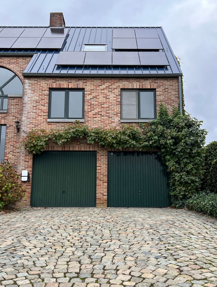 A brick home with rooftop solar panels under an overcast sky